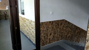 A hotel entrance with a wooden floor, a wall with a textured pattern, and a door. - Wanluoyuan Theme Hotel (Antu)