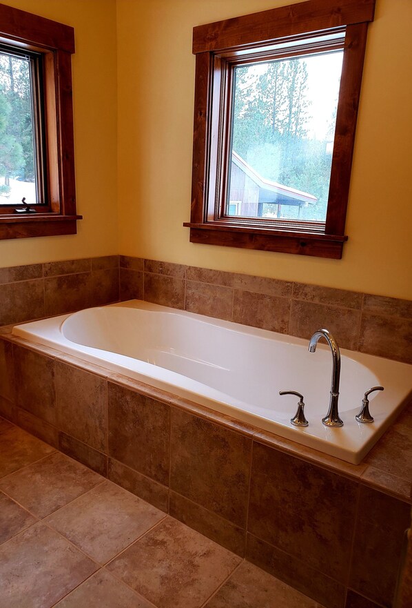 A modern bathroom with a freestanding bathtub, wooden window frames, and tiled walls. - Mountain air and room to roam! (New Meadows)