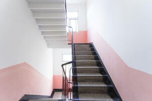 Una escalera con barandilla que lleva a un rellano con ventana.