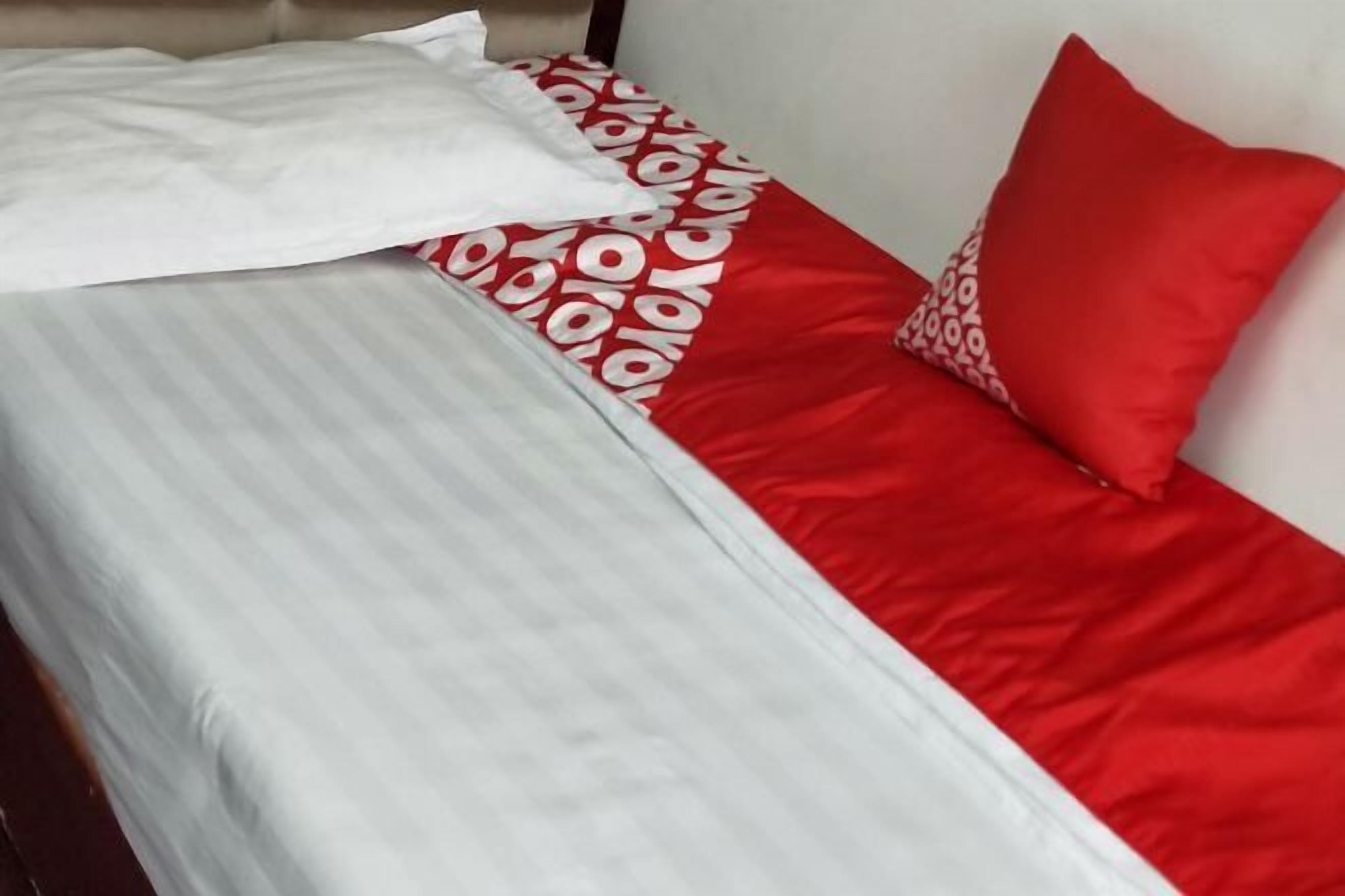 Una cama con una colcha a rayas y almohadas estampadas en rojo y blanco.