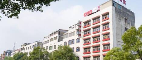 A multi-story building with a red and white facade, multiple balconies, and signage indicating it is a hotel.