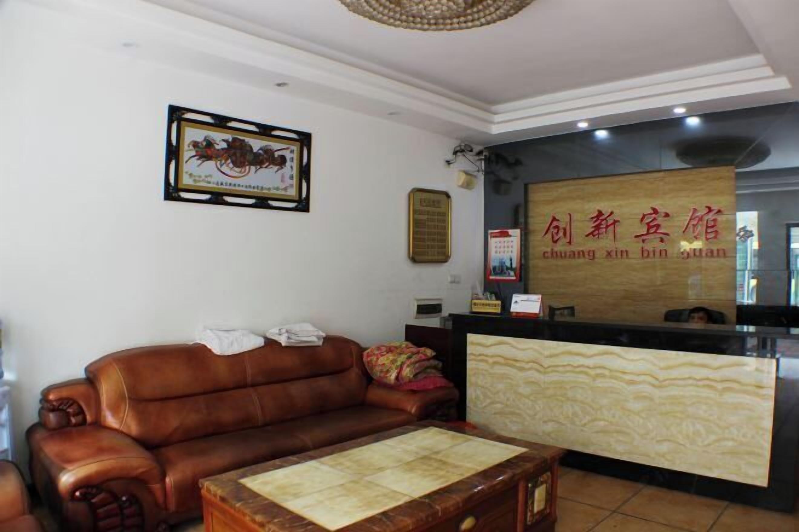 A reception area with a brown leather sofa, a wooden coffee table, and a reception desk with a marble-like surface.