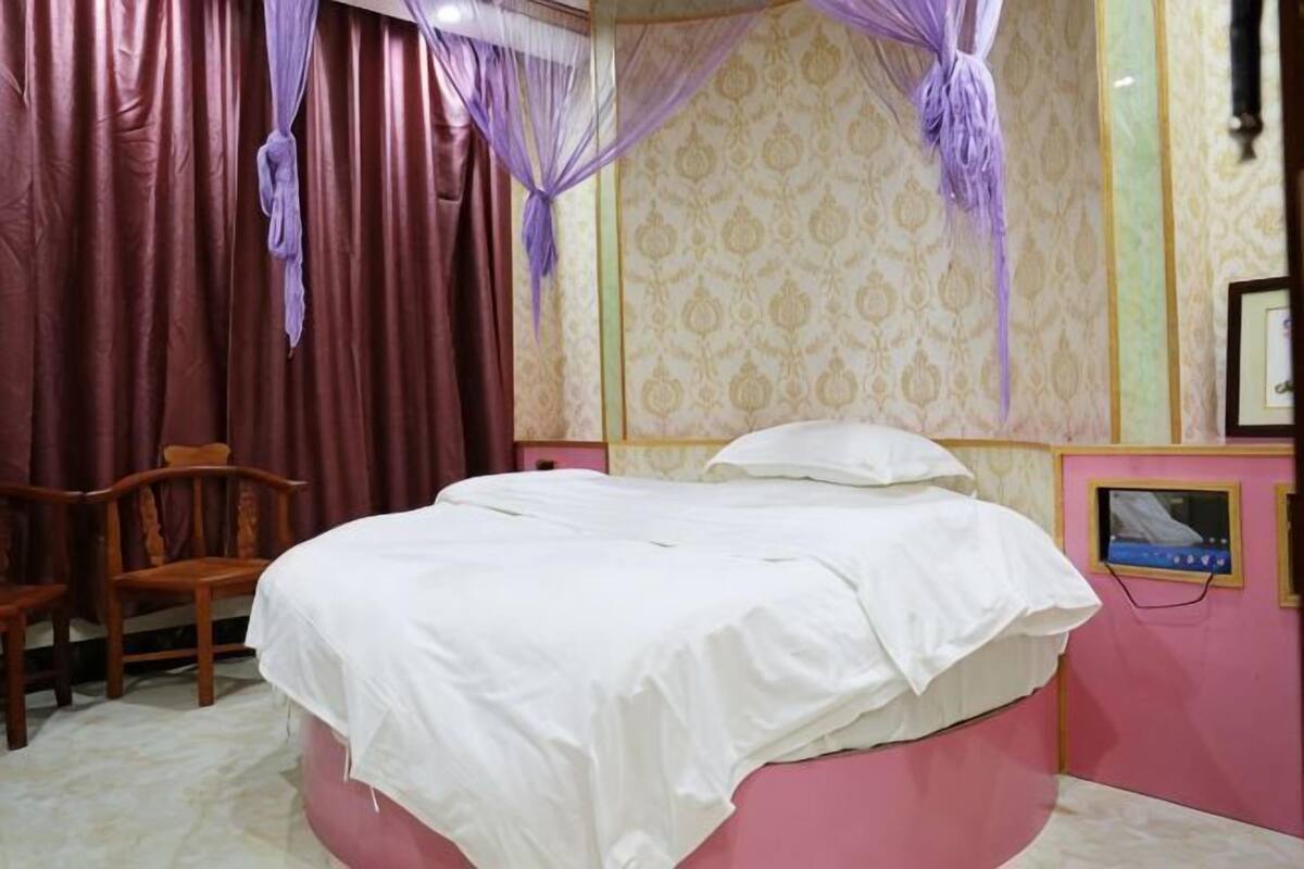 Un dormitorio con cama, una silla y una cortina.