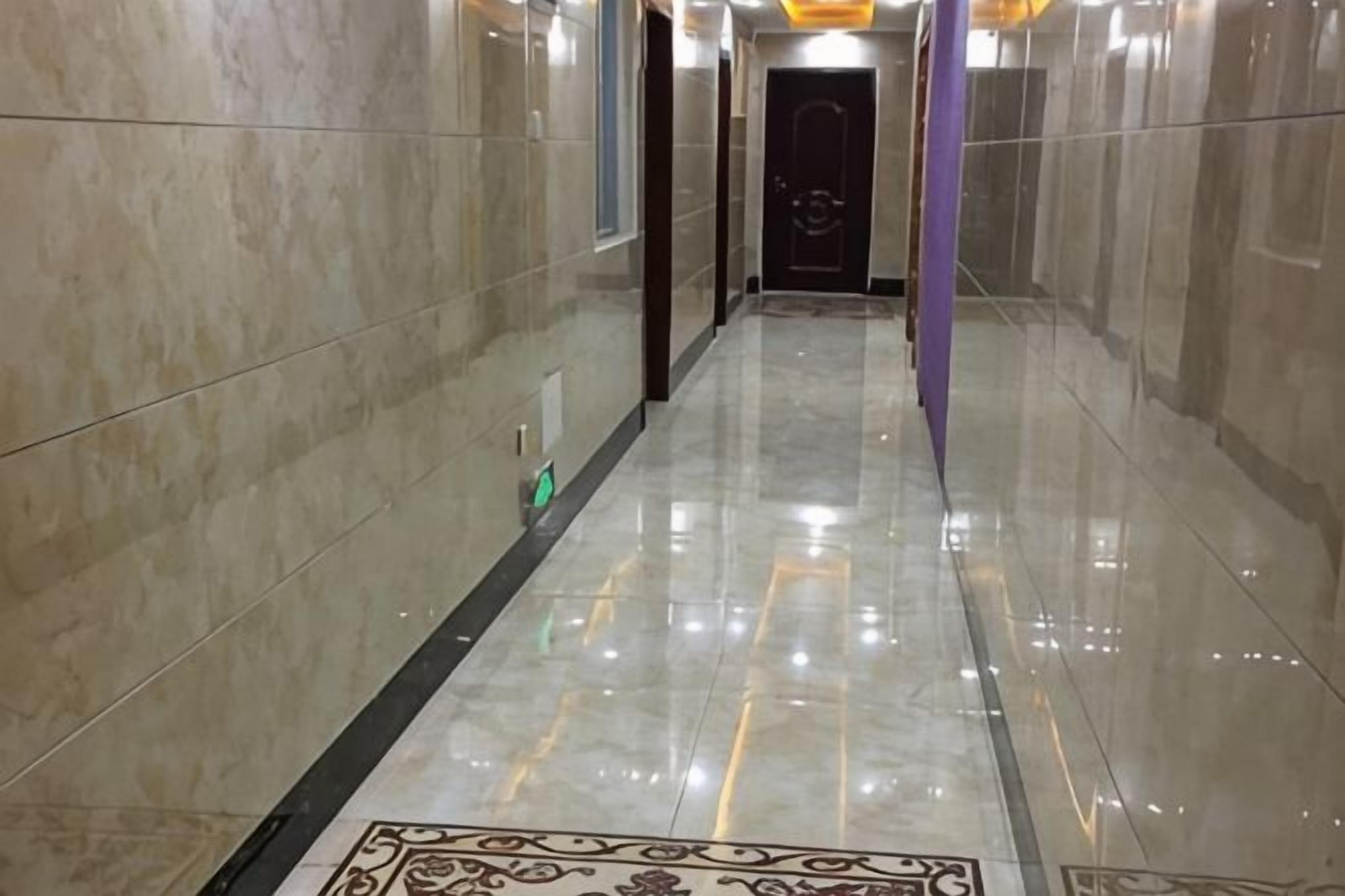 A hallway with a polished floor and a patterned rug.