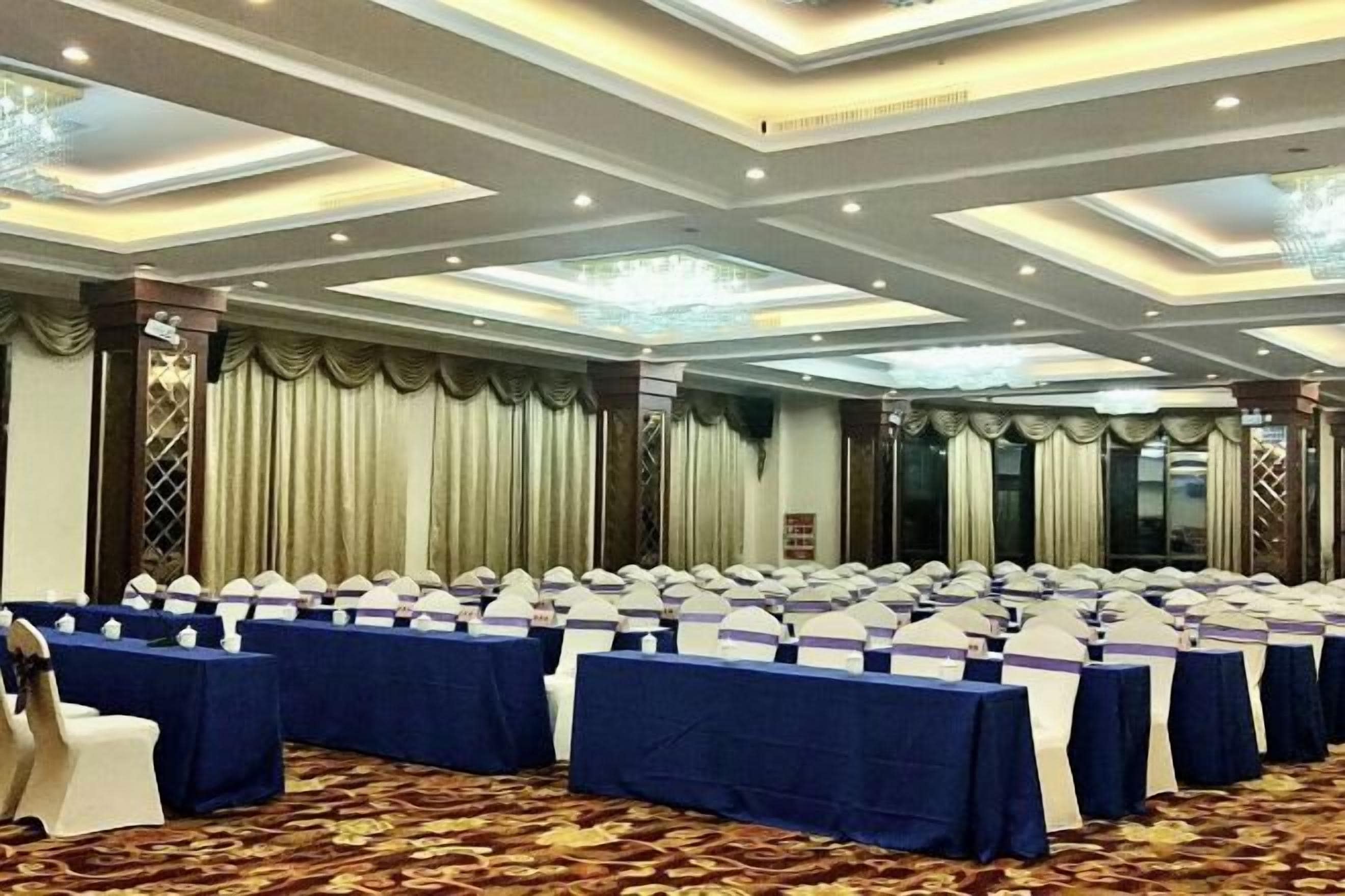 A conference room with rows of tables, chairs, and a carpeted floor.