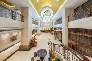 A spacious hotel lobby with a grand chandelier, multiple seating areas, and a central staircase. - Wanmin International Hotel (Longlin)
