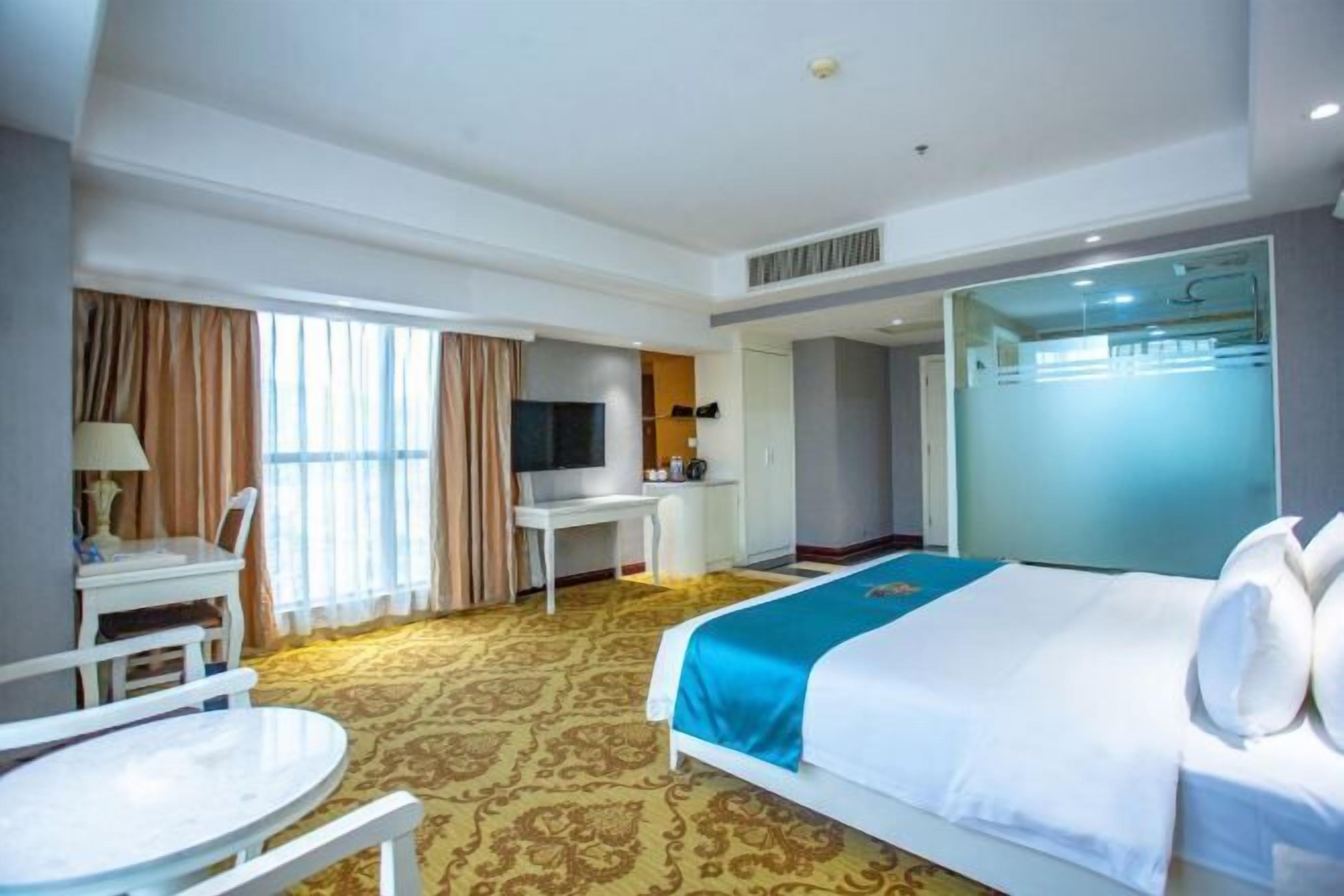 Une chambre d’hôtel comprenant un lit, un bureau, une chaise, une télévision et une salle de bain.