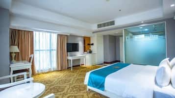 A hotel room with a bed, a desk, a chair, a TV, and a bathroom.