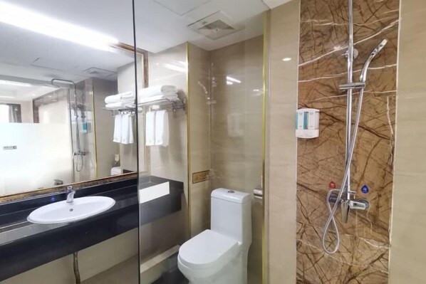 A bathroom with a glass partition, a white toilet, a black countertop with a sink, and a shower area with a marble wall. - Wanmin International Hotel (Longlin)
