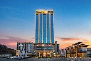 A modern hotel with a tall central tower, a ground-level building with a glass facade, and a parking lot. - Wanmin International Hotel (Longlin)