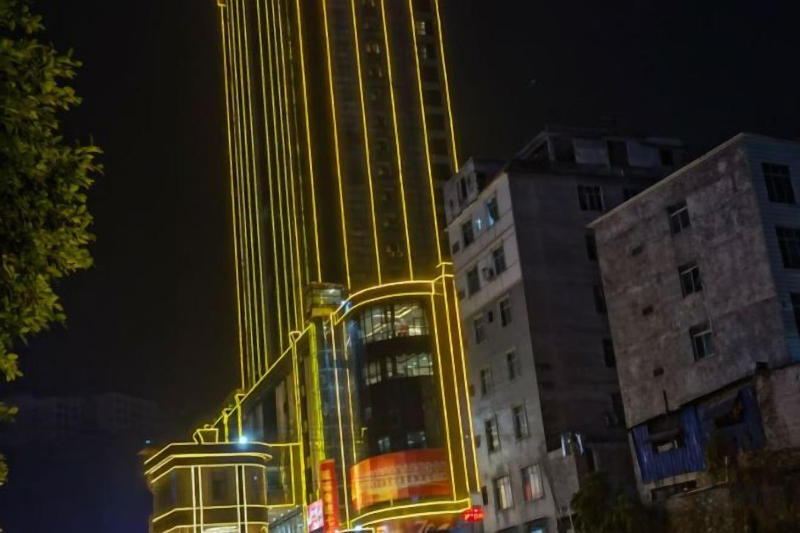 Un immeuble de grande hauteur, avec des lignes verticales illuminées et une grande enseigne publicitaire.