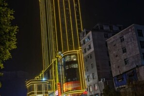 A high-rise building with illuminated vertical lines and a large advertisement banner. - Wanmin International Hotel (Longlin)