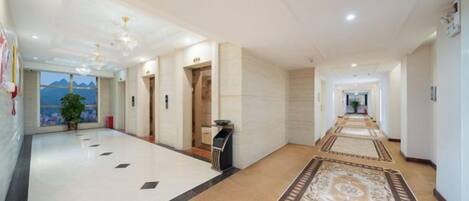 A hotel lobby with a long corridor, a reception desk, and a view of the mountains.