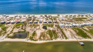 Ett flygbildsfoto av en fastighet vid kusten med flera byggnader, en strand och en stor vattenyta.