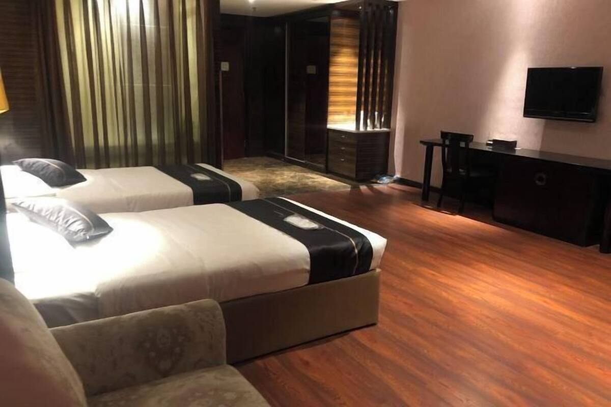A hotel room with two beds, a desk, a TV, and a wardrobe.