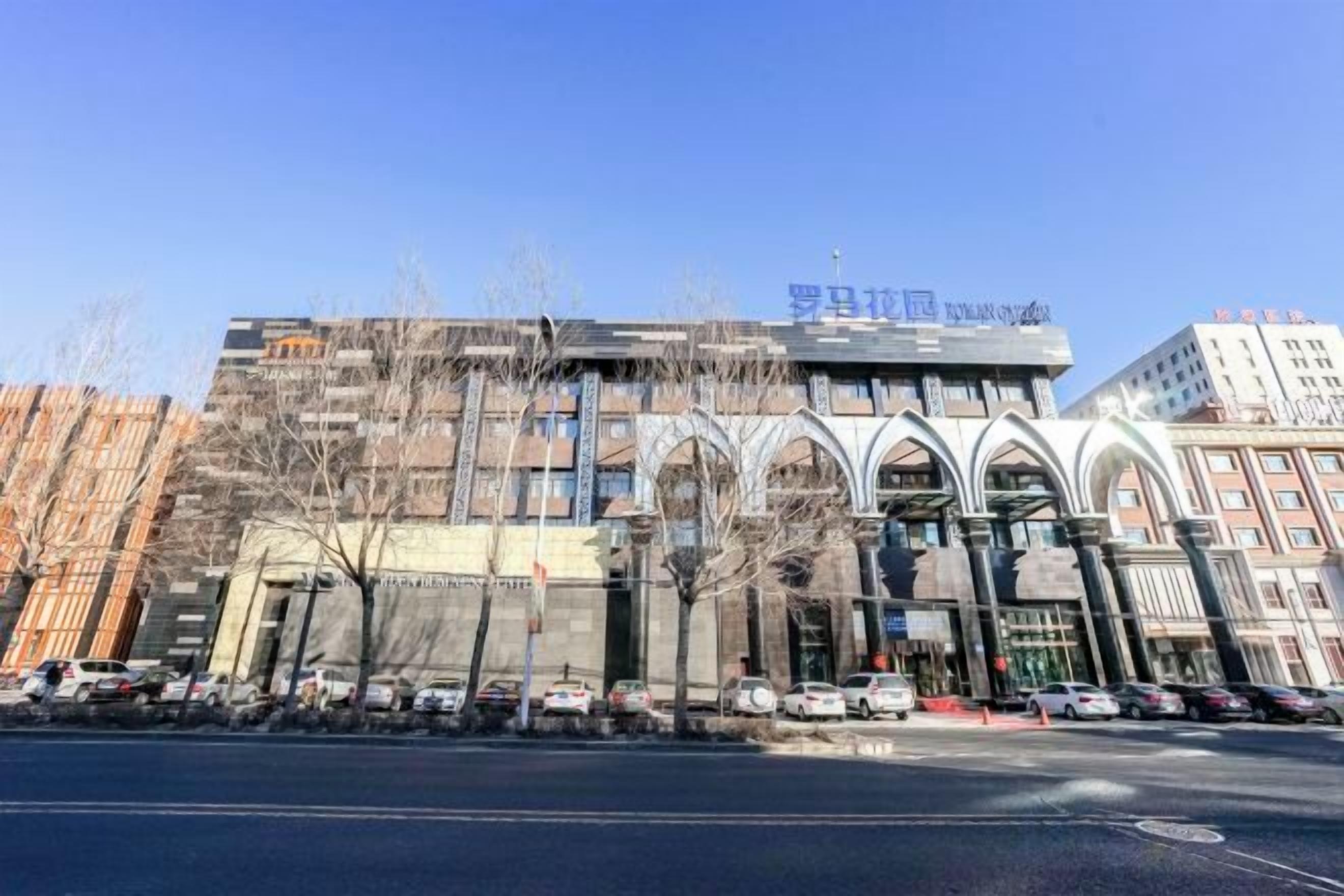 A multi-story building with a modern architectural design, featuring a prominent entrance with arched windows and a flat roof.