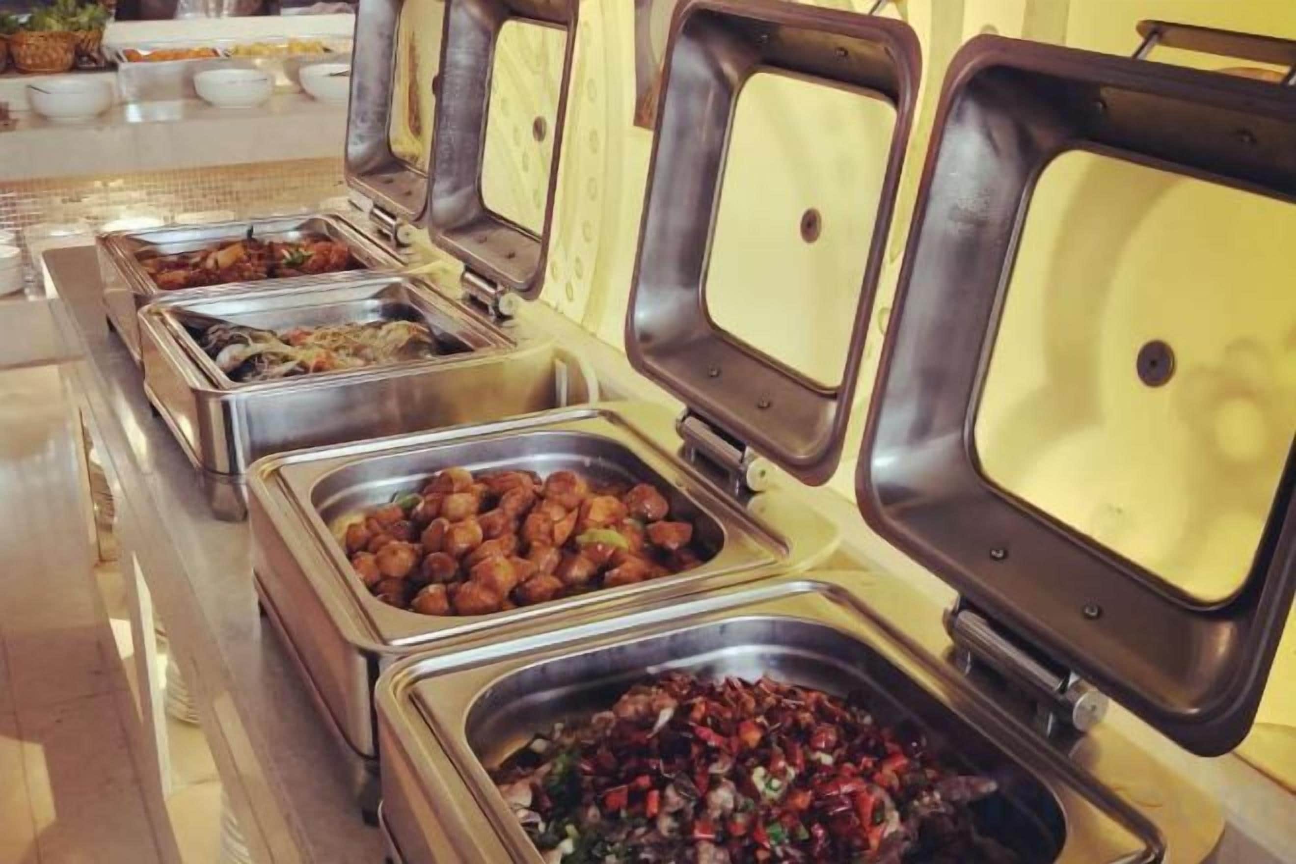 A buffet with multiple food stations, each with a metal container and a lid.
