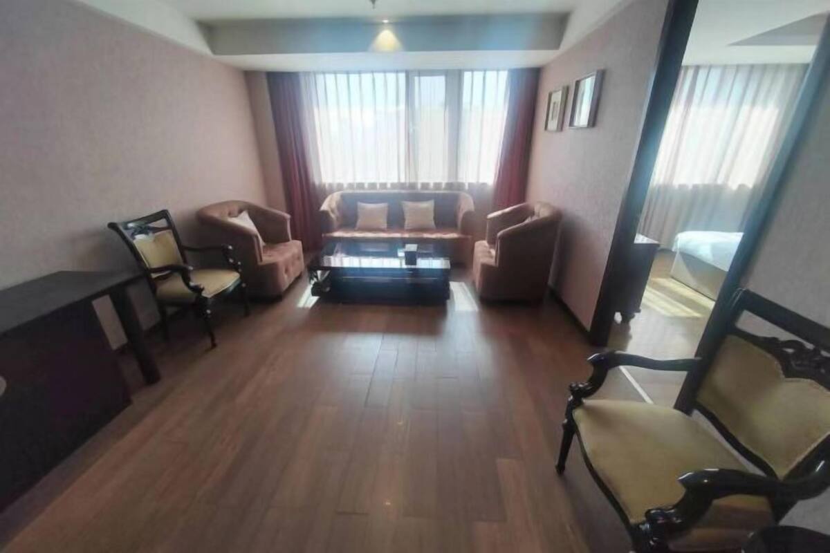 A hotel room with a sofa set, a coffee table, and a desk.