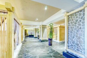 A hotel corridor with a stone floor, wooden doors, and a patterned wall. - Roman Garden Business Center (Mudanjiang)