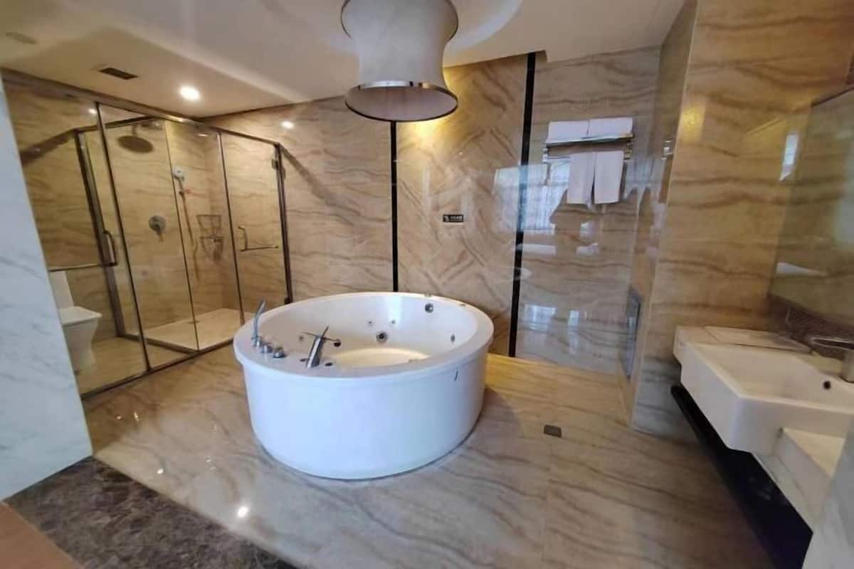 A modern bathroom with a freestanding bathtub, a glass-enclosed shower, and a separate sink area.