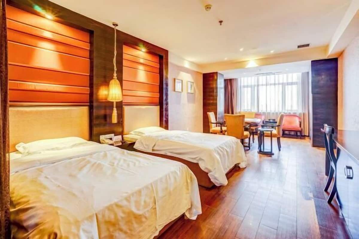 A hotel room with two beds, a dining area, and a large window.