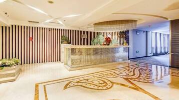 A hotel reception area with a reception desk, a patterned floor, and a modern interior design.
