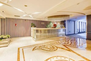 A hotel reception area with a reception desk, a patterned floor, and a modern interior design. - Roman Garden Business Center (Mudanjiang)