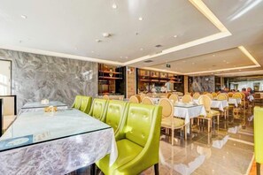 A restaurant with marble walls, green upholstered chairs, and tables with glass tops. - Roman Garden Business Center (Mudanjiang)