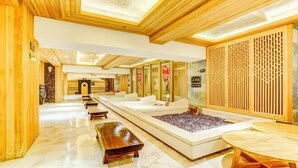 A spa area with wooden paneling, a massage table, and a seating area with benches. - Roman Garden Business Center (Mudanjiang)