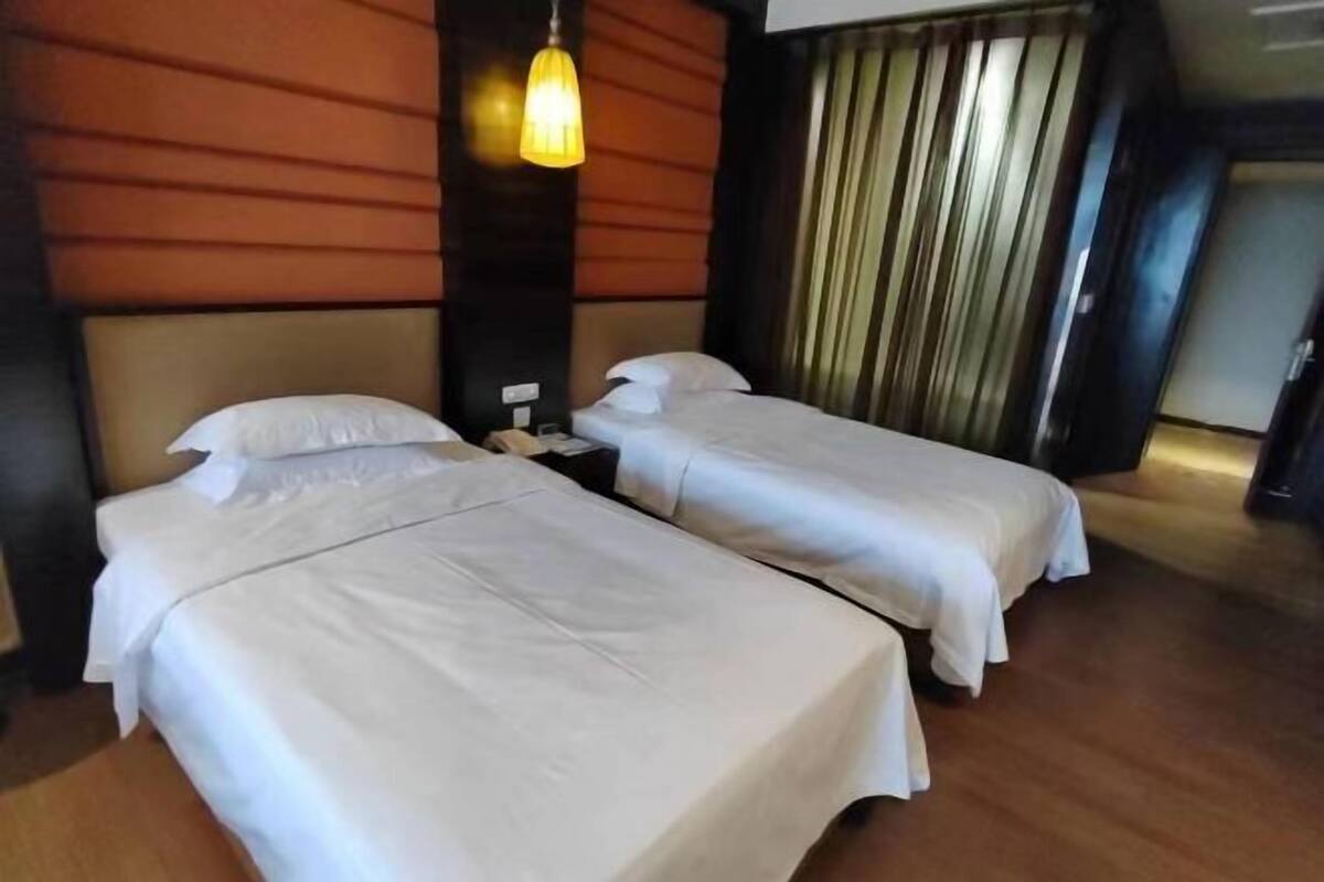 A hotel room with two single beds, a wooden floor, and a modern design.
