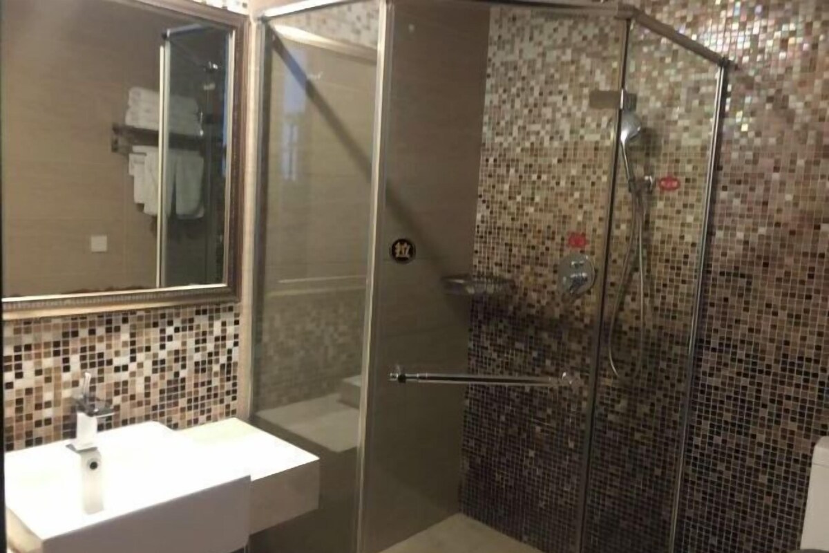 A bathroom with a glass-enclosed shower, a white sink, and a tiled backsplash.