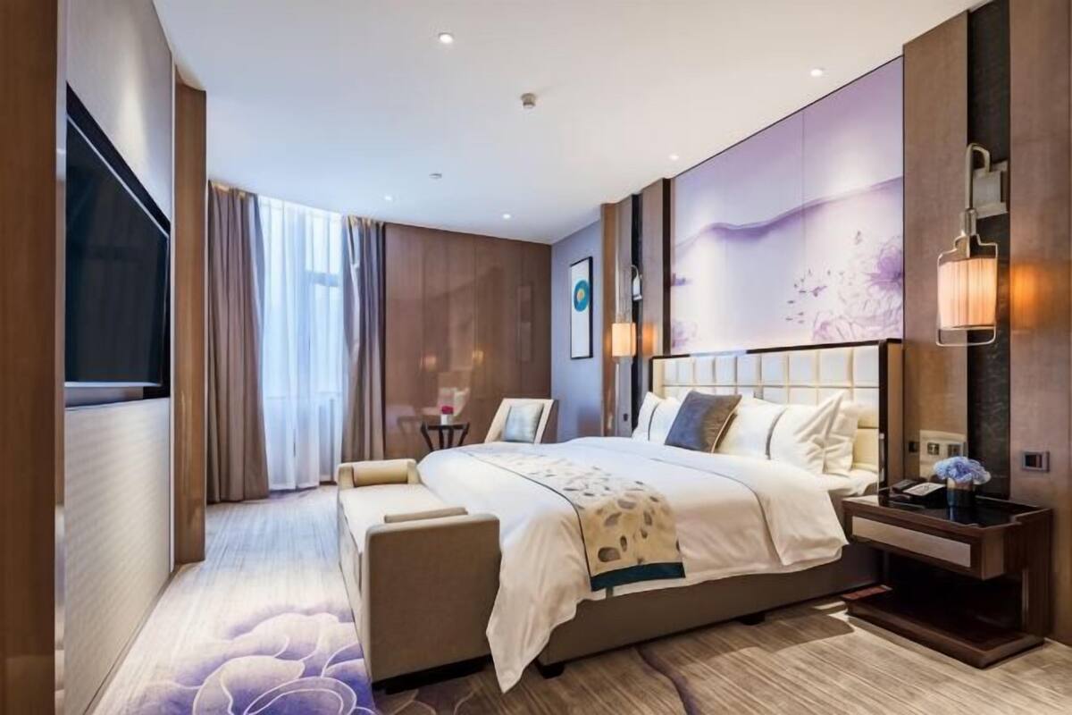 A modern hotel room with a large bed, a desk, and a TV.