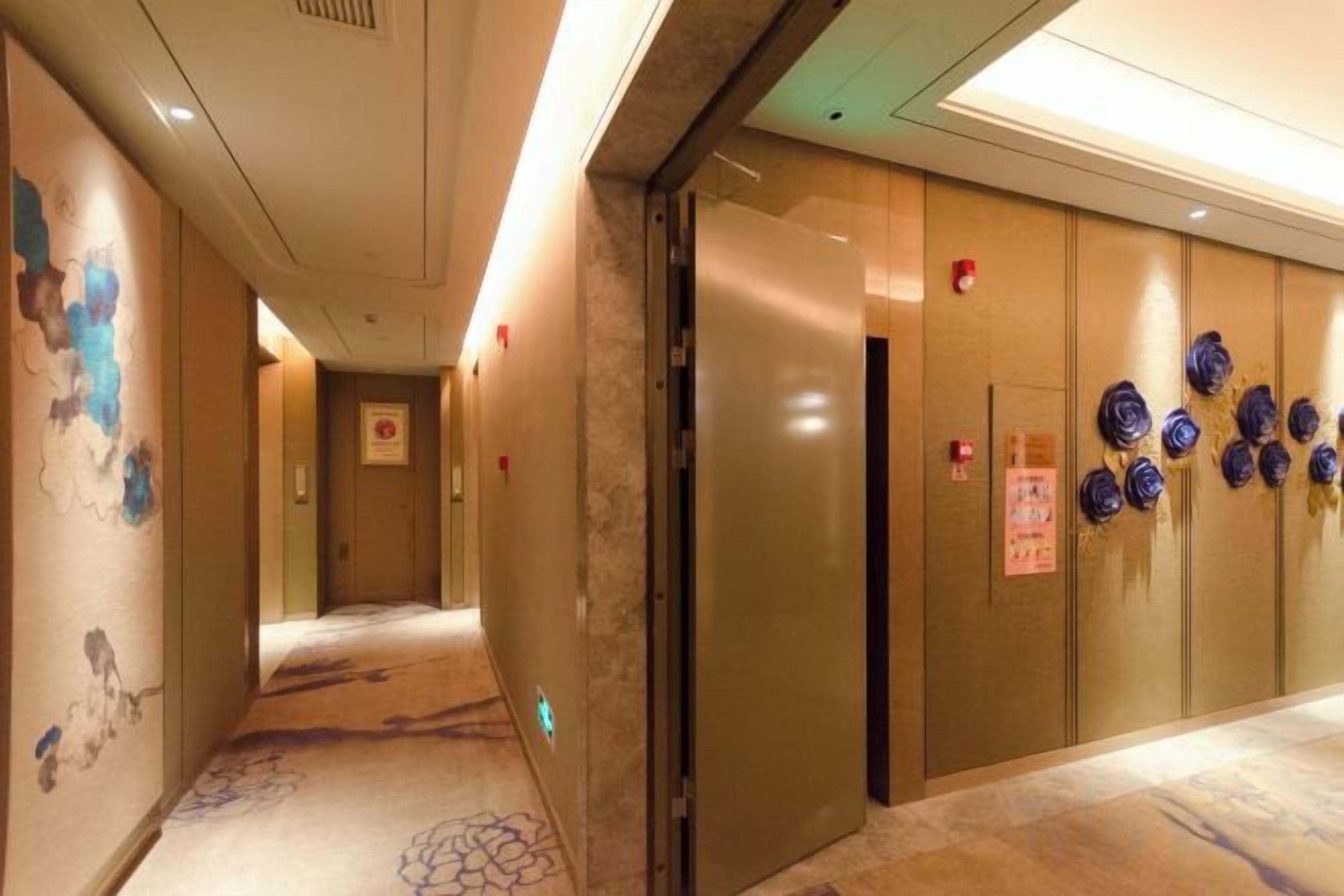 Un pasillo de hotel con piso alfombrado, una pared con diseño floral y una puerta con un letrero.