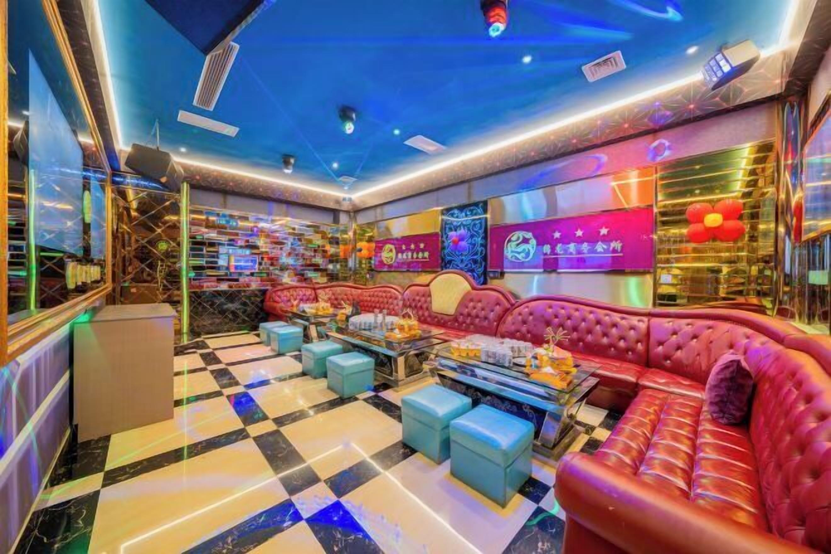 Un salón vibrante con piso a cuadros, un sofá rojo y una zona de bar con diversos objetos.