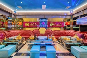 A vibrant lounge area with red upholstered seating, glass tables, and decorative elements including red banners and a floral design on the wall. - Jinlong Hotel (Tianlin)