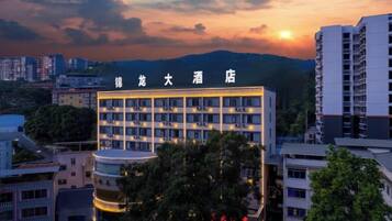 Un hotel de varios pisos, con un letrero llamativo y vistas de edificios y colinas circundantes.