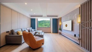 Una sala de estar moderna con un sofá, un sillón reclinable, una mesa de centro y un televisor montado en la pared.