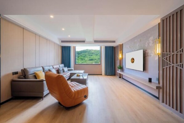 A modern living room with a sofa set, a recliner, a coffee table, and a TV mounted on the wall. - Jinlong Hotel (Tianlin)