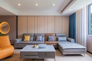 Een moderne woonkamer met een modulaire bank, een salontafel en een groot raam met gordijnen.