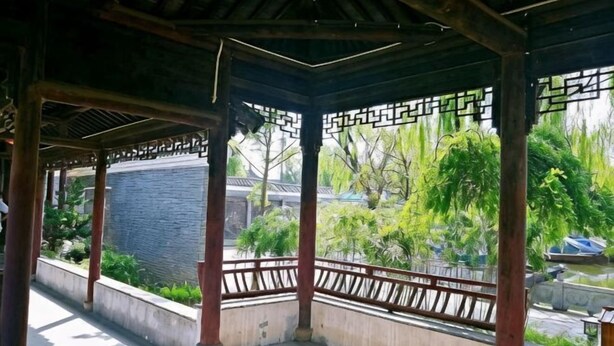 A covered pavilion with a view of a garden and a water body. - Wan Fu Hostel (Kunshan)