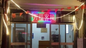 A hotel entrance with a neon sign, glass doors, and a visible room number. - Wan Fu Hostel (Kunshan)
