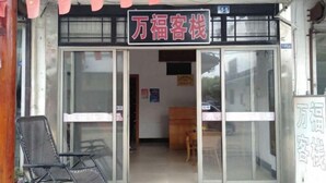 A storefront with a sign reading "万福客栈" and a number "105" above the entrance. - Wan Fu Hostel (Kunshan)