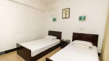 A room with two single beds, a nightstand, a wall-mounted light, and a framed picture.
