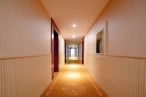 A hotel hallway with a carpeted floor, wooden doors, and a light-colored wall. - Fenglin Hotel (Sandu)