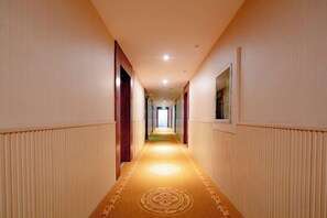 A hotel corridor with a carpeted floor, doors on both sides, and a light source at the end. - Fenglin Hotel (Sandu)