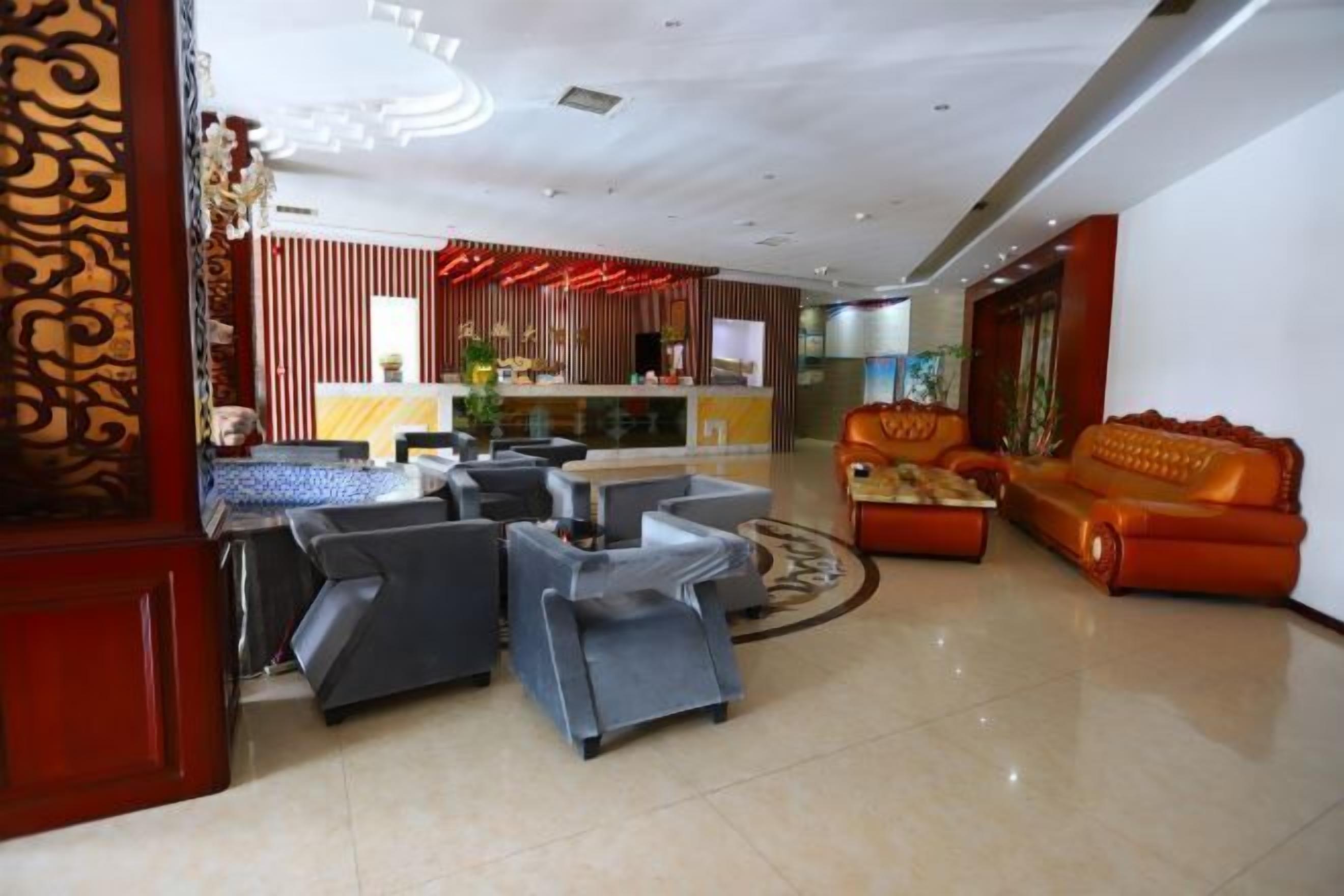 A hotel lobby with a reception desk, seating area with sofas, and a decorative wall.