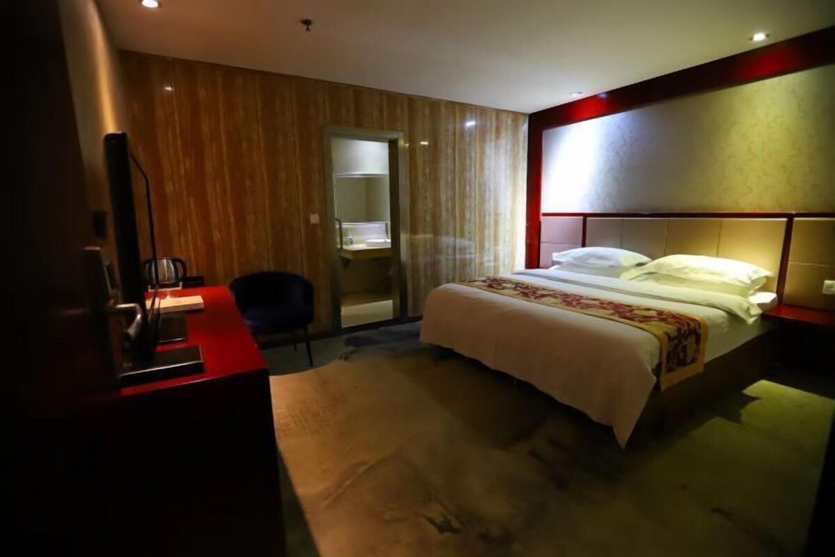 Une chambre d’hôtel avec un lit, un bureau, une chaise et un miroir.
