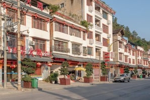 A row of traditional buildings with balconies, some with red decorations, and a street in front. - Fenglin Hotel (Sandu)