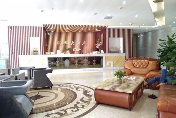 A modern lobby with a reception desk, leather seating, a patterned rug, and a large plant. - Fenglin Hotel (Sandu)