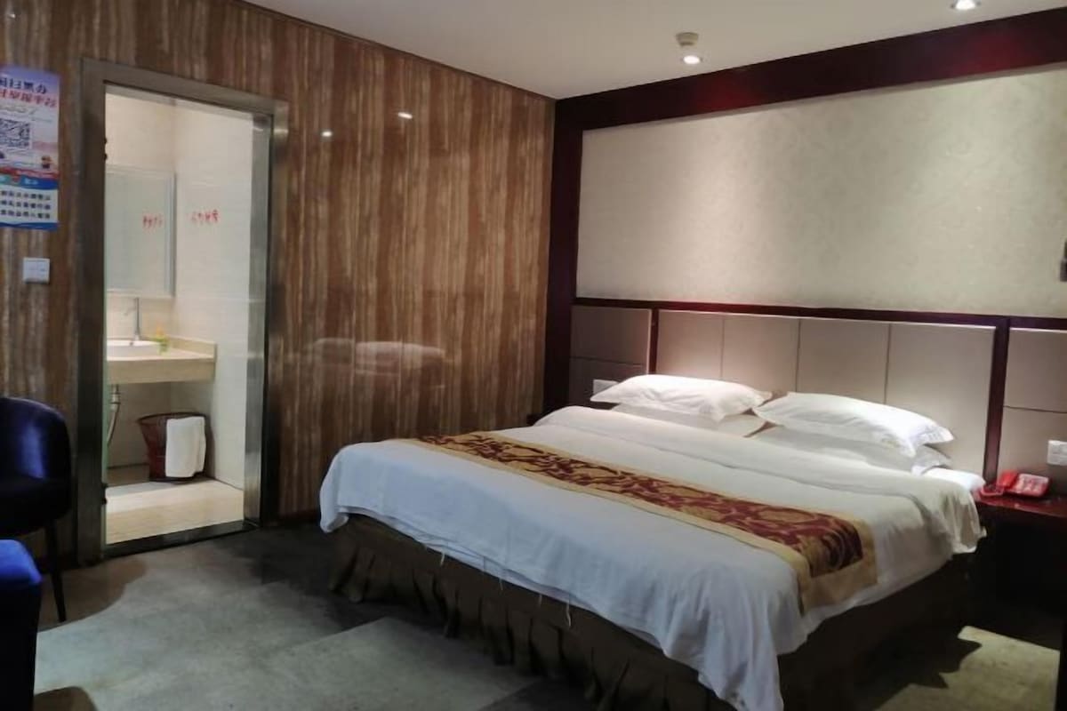 A hotel room with a bed, a desk, a chair, a wardrobe, and a bathroom.